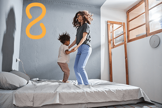 Single Mum Jumping for joy on a bed in new home