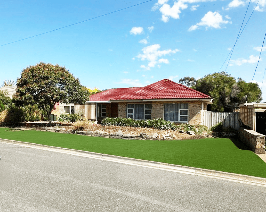A charming single-story brick home with a red tile roof, landscaped front yard, and a driveway on a quiet suburban street.