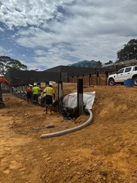 Construction site with workers installing supports and preparing land for building a new home.