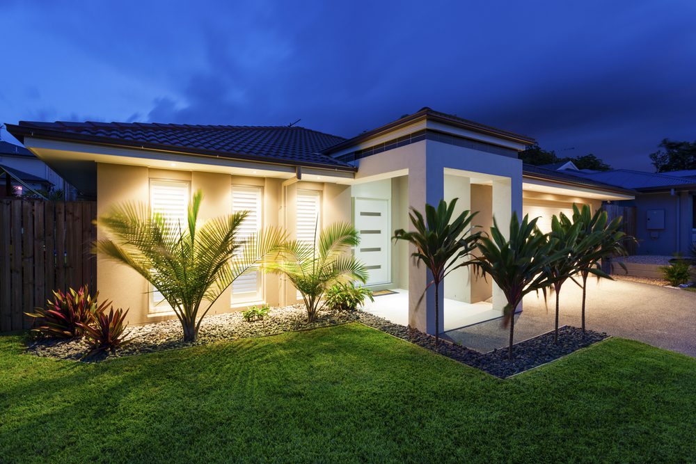Contemporary single-storey Australian home with tropical landscaping, illuminated at twilight