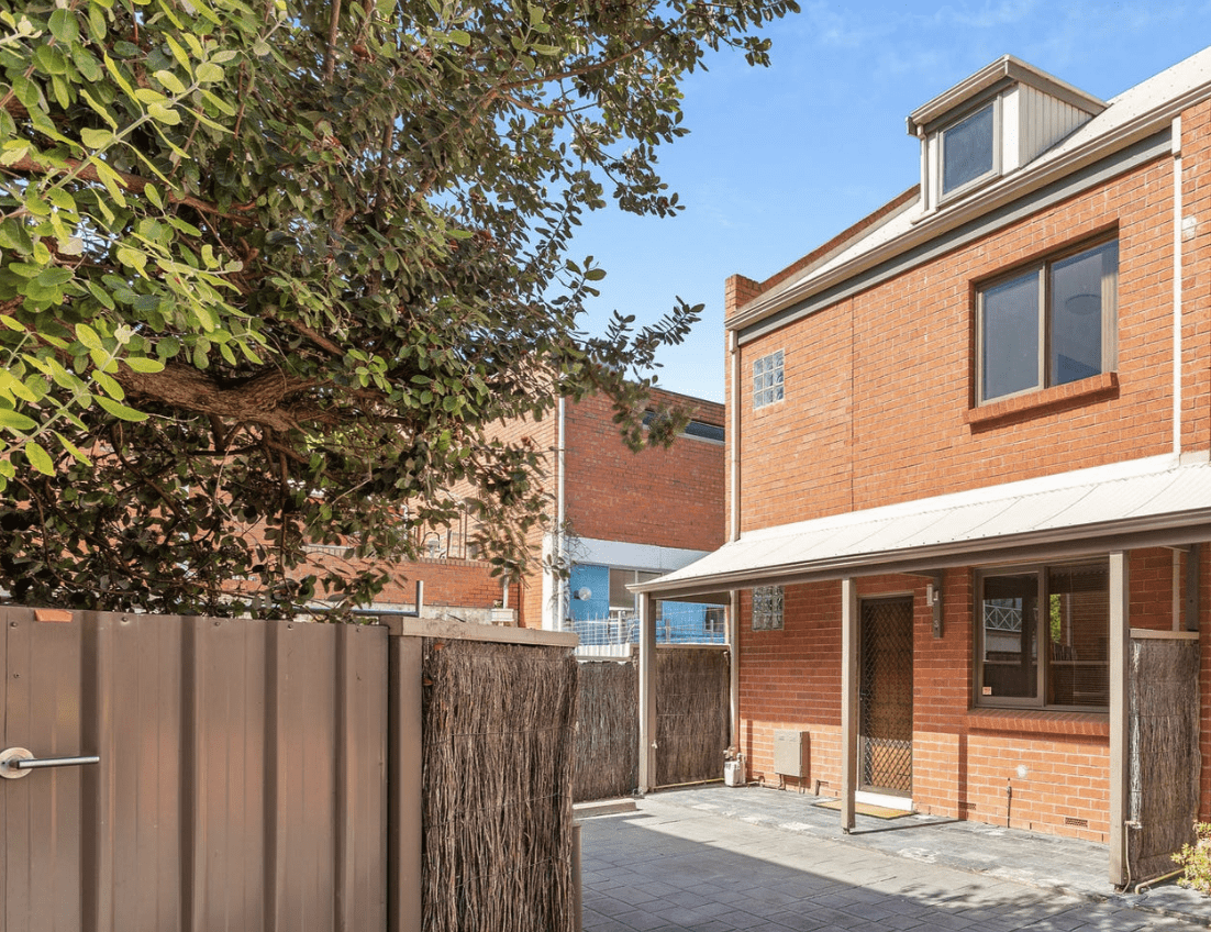 Exterior of a three-storey red brick townhouse in Adelaide with private courtyard and off-street entry