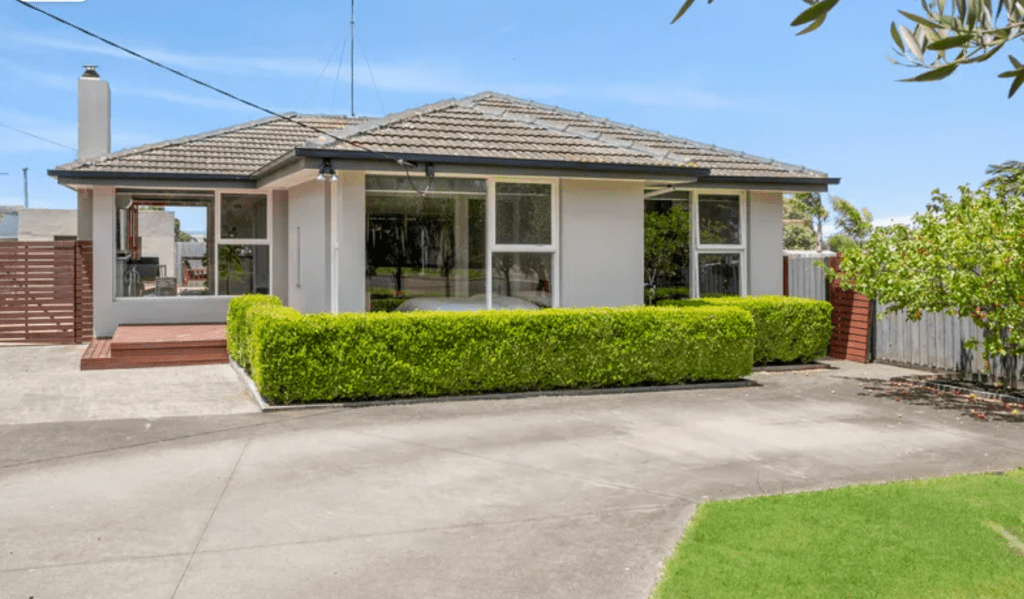 Single-storey renovated home in Grovedale, VIC with tiled roof, large front windows, manicured hedges, wide driveway and landscaped front yard on a 598m² block.